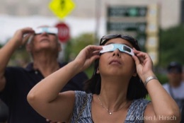 Woman with eclipse glasses looking up